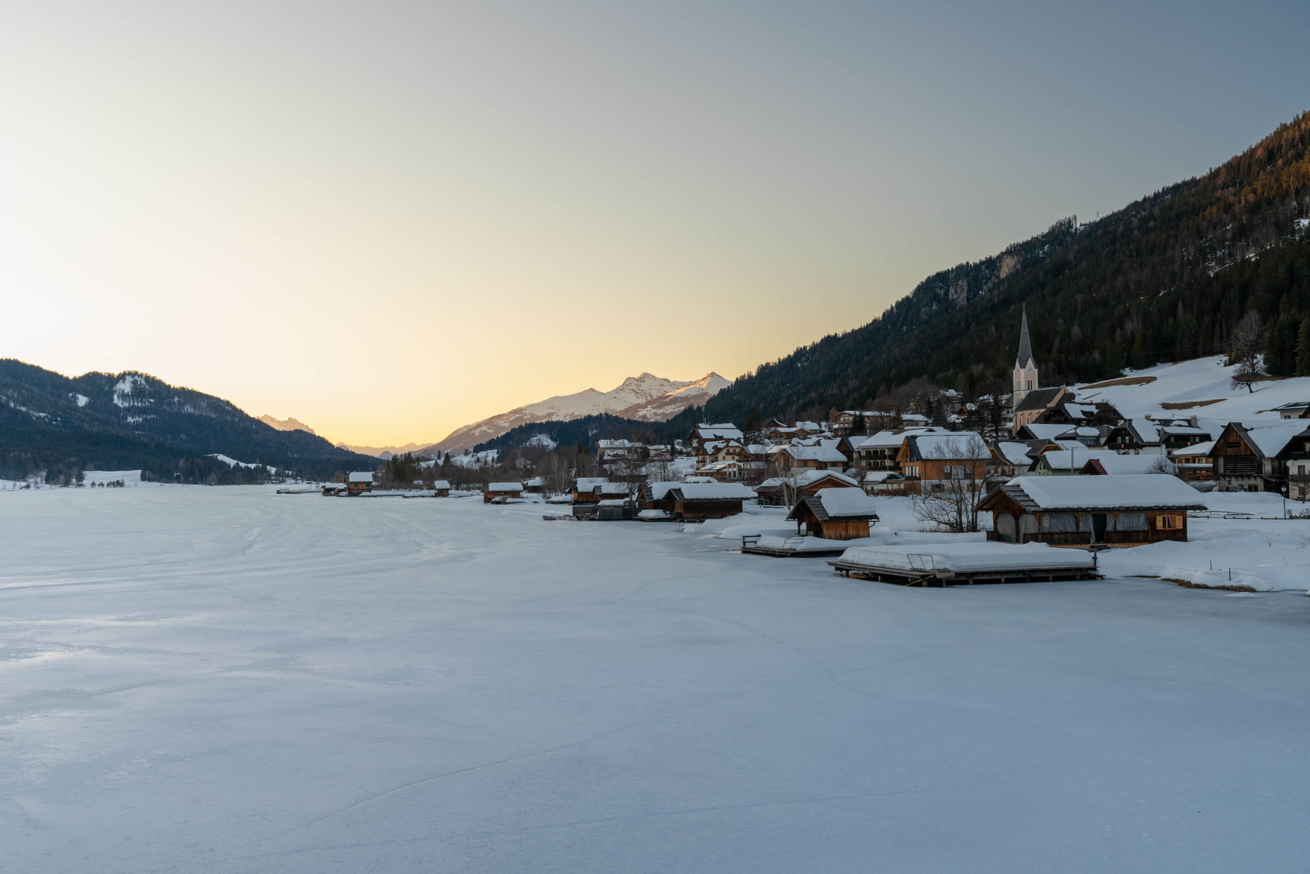 Techendorf at sunset on a frozen and snow covered lake Weissensee, Carinthia