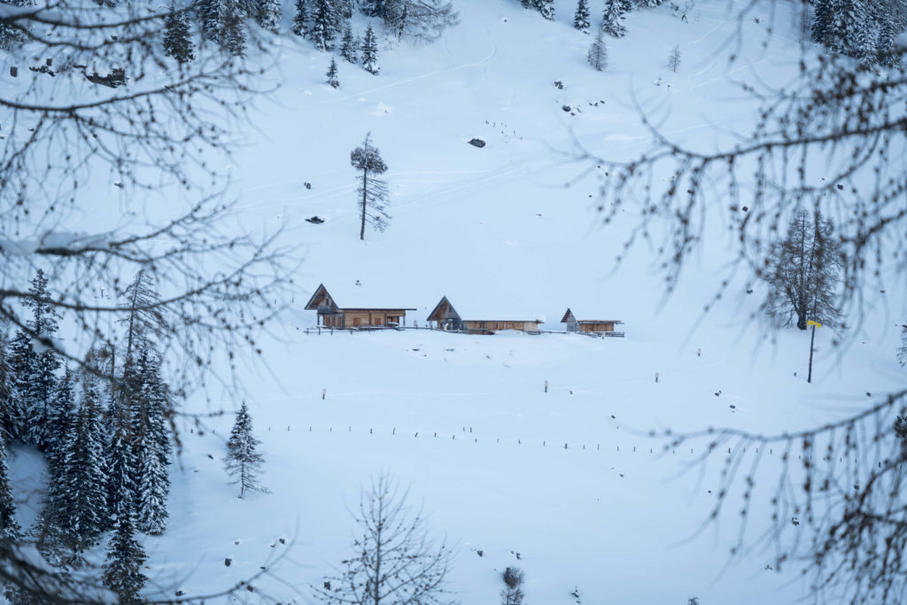 Three winter wooden cabins in a line covered in a blanket of snow framed by the forest, Katschberg, Carinthia