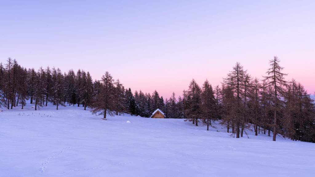 Winter hut surrounded by snow in the mountains of Hochrindl during a pink sunset, Carinthia