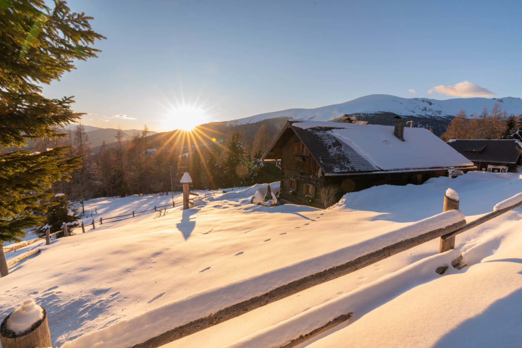 Winter hut covered in snow in the mountains of Hochrindl at sunset, Carinthia