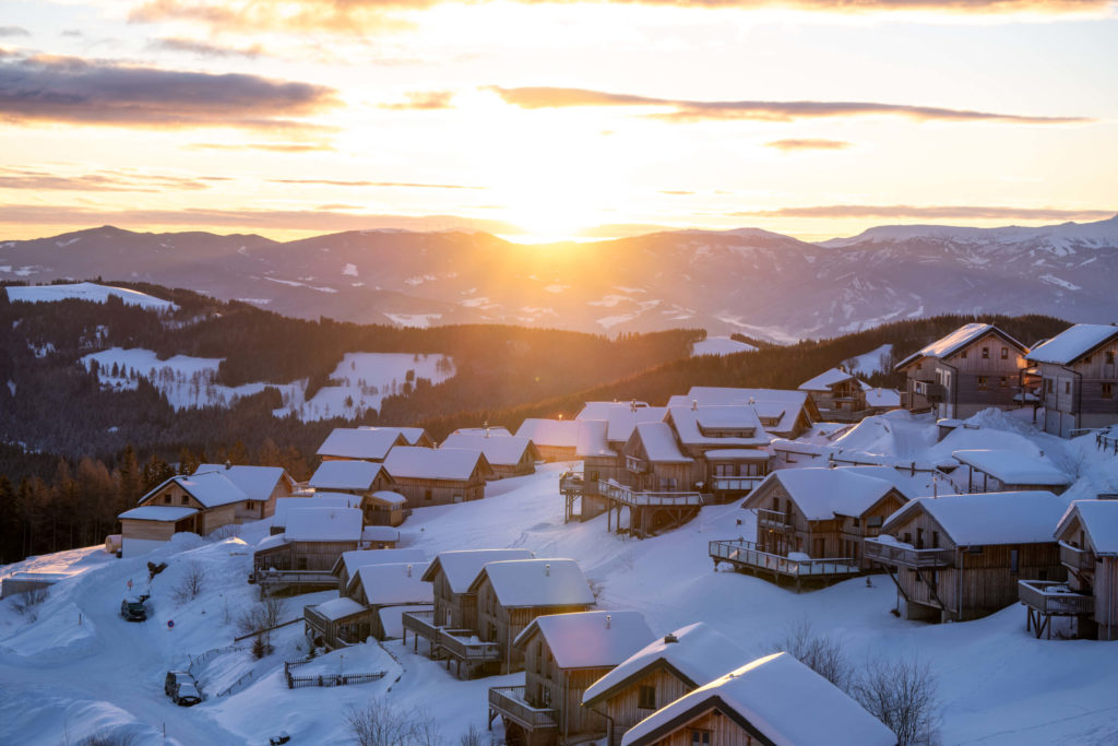 Winter sunrise over alpine chalets covered in snow and the Koralpe mountains, Klippitztörl, Carinthia