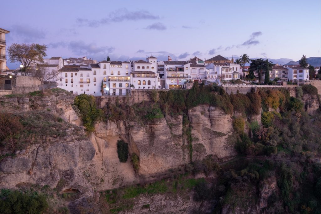 Buildings hanging on the edge of the cliff after sunset in Ronda, Spain