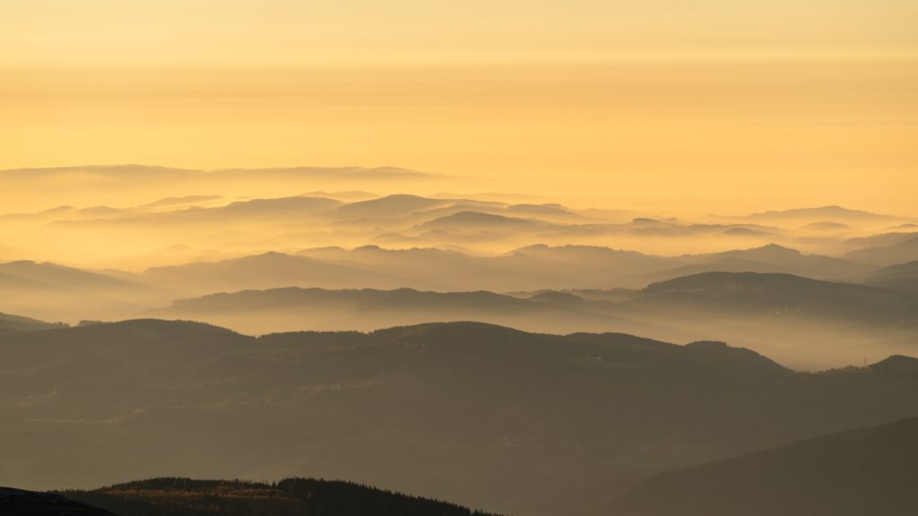 Layers of warm light over the hills surrounding Schneeberg with hazy light from raging forest fires, Lower Austria, Austria