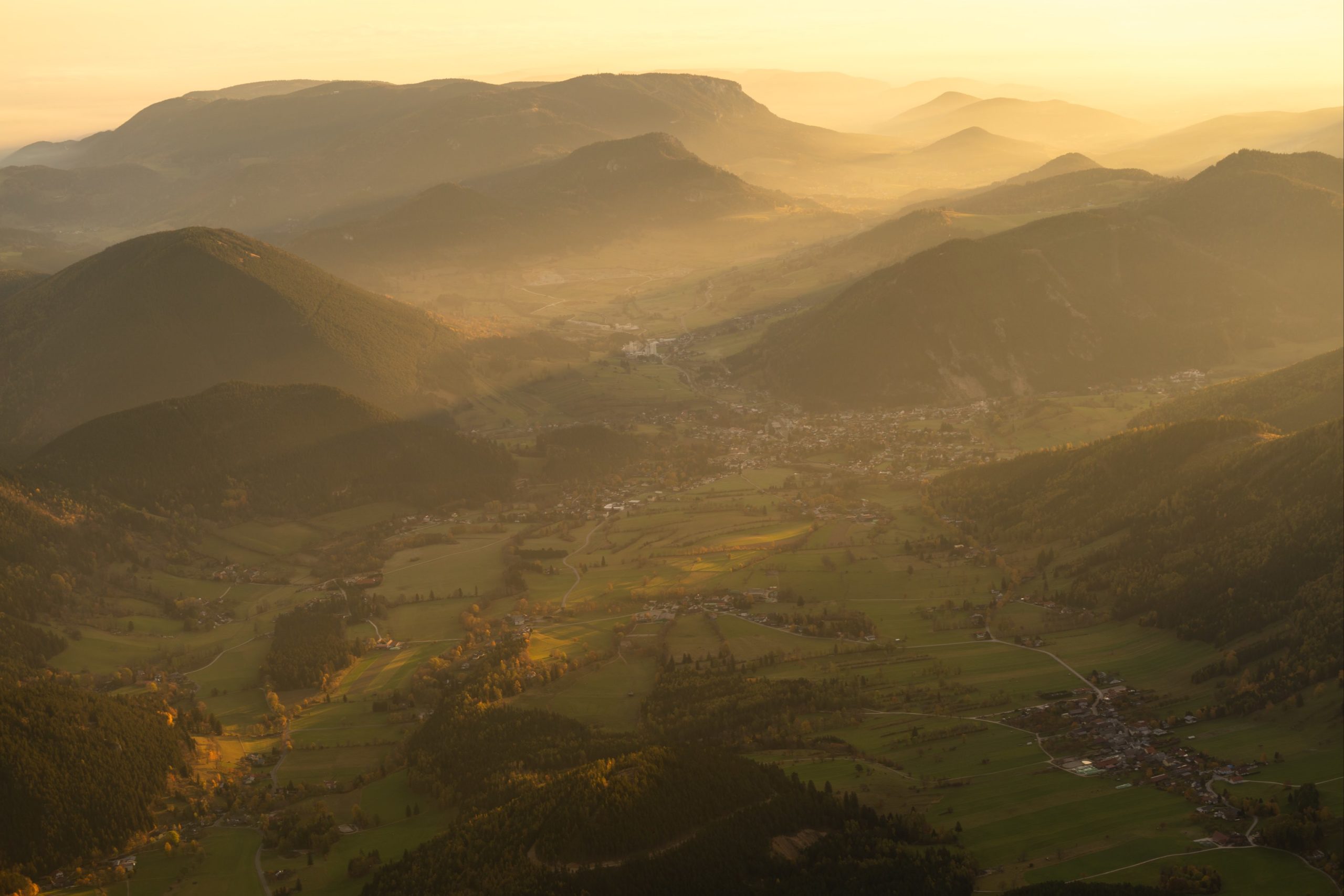 Warm autumn morning light and fog over Puchberg village and the surrounding mountains during sunrise from the top of Schneeberg