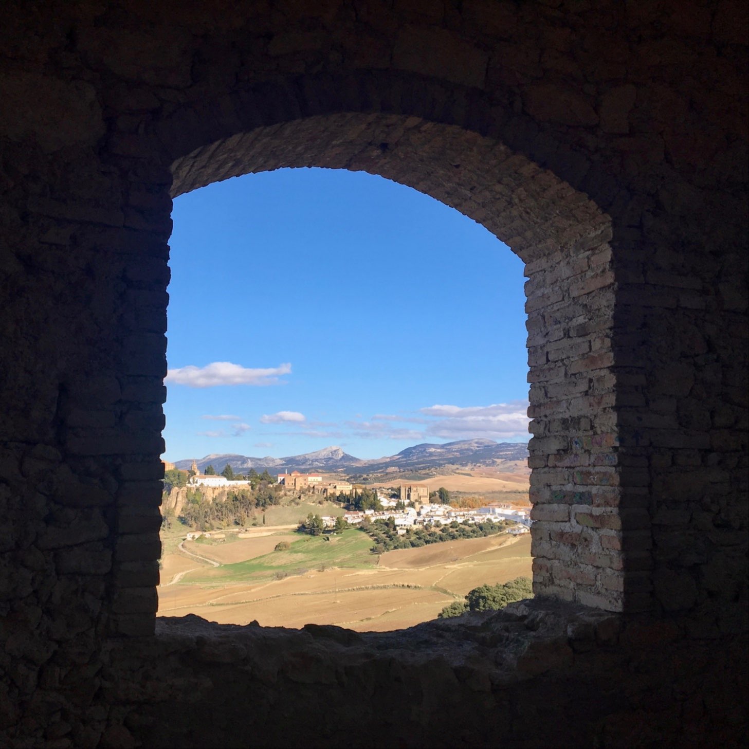 Ronda on a sunny day through the window of an abandoned building with Sierra Nevada mountains, Spain