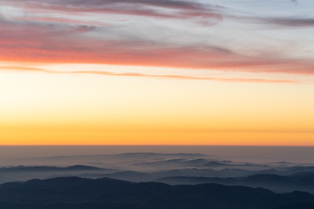 Thick fog on the hills surrounding Schneeberg with vibrant colours during sunrise, Lower Austria, Austria