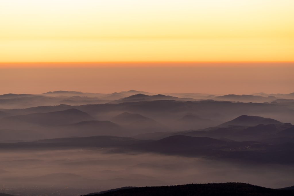 Thick fog on the hills surrounding Schneeberg at sunrise