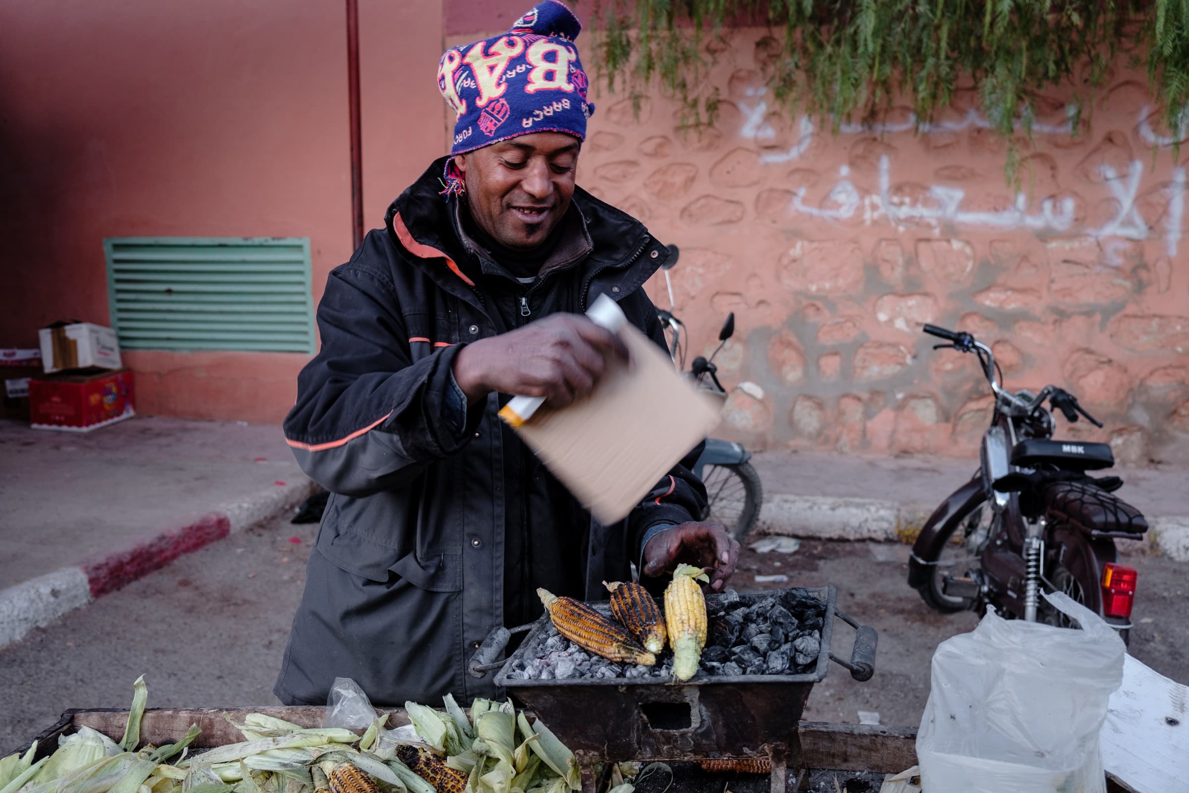 A man cooking corn on the cob on coals in Tinghir