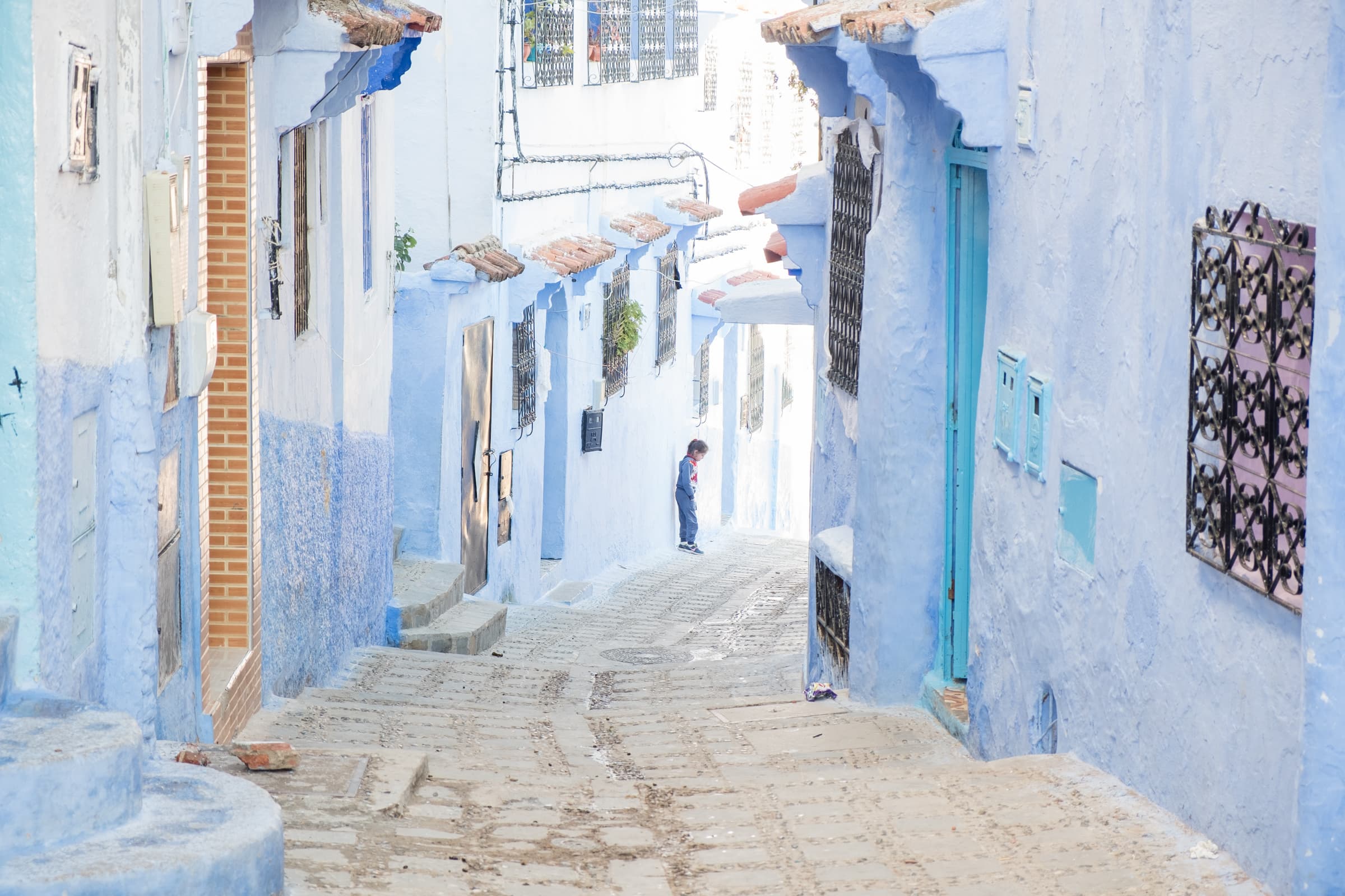 A small girl standing in the blue streets of Chefchaouen, Morocco