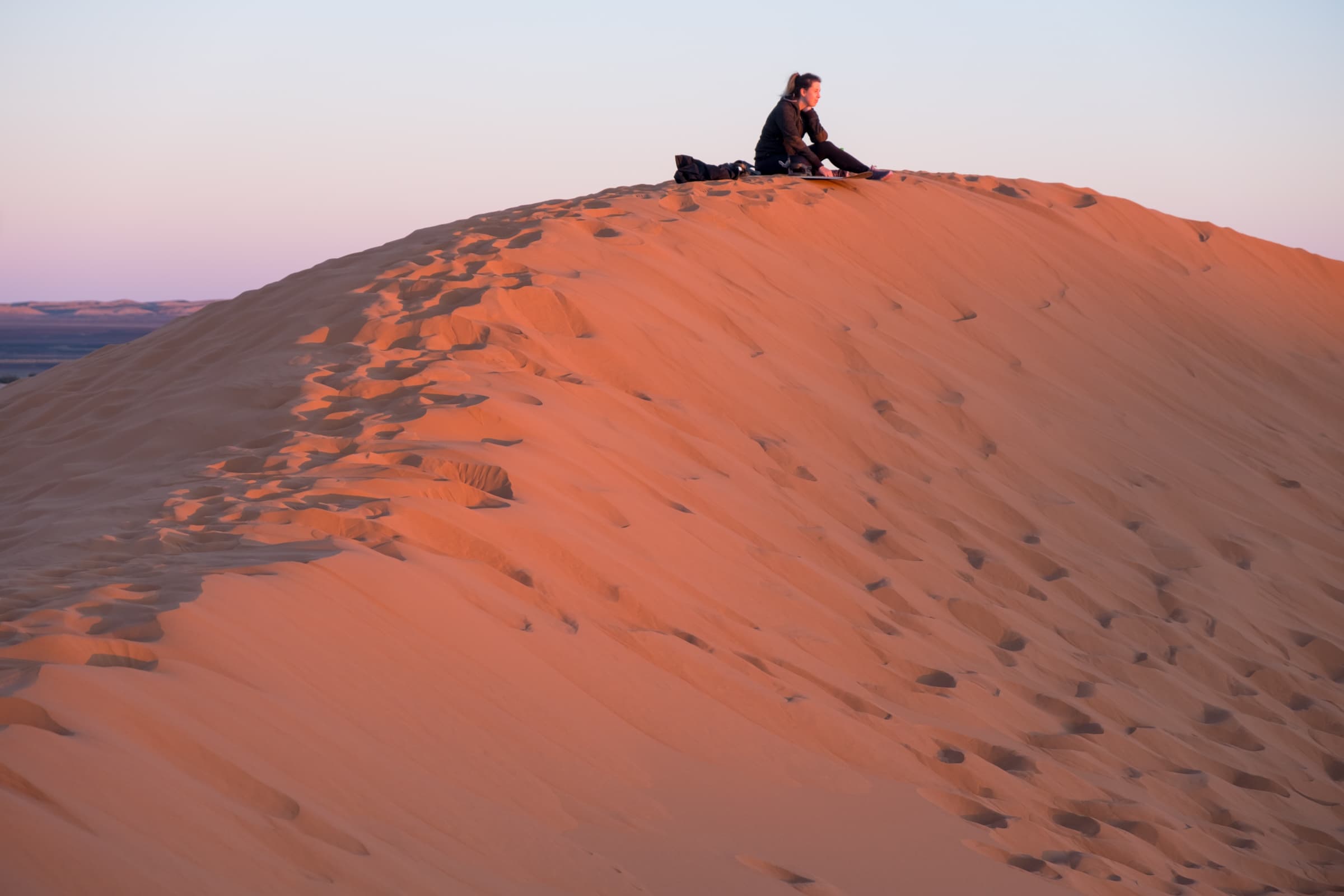 Caroline sat on top of a sand dune at sunset