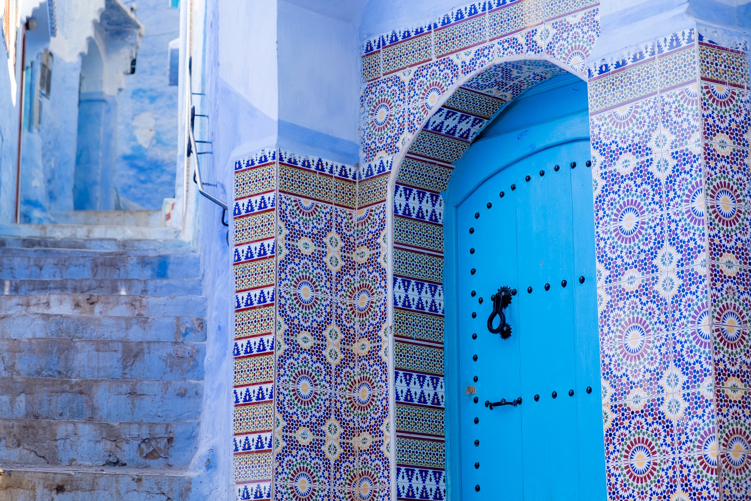 Intricately decorated tiled door and blue staircase, Chefchaouen, Morocco