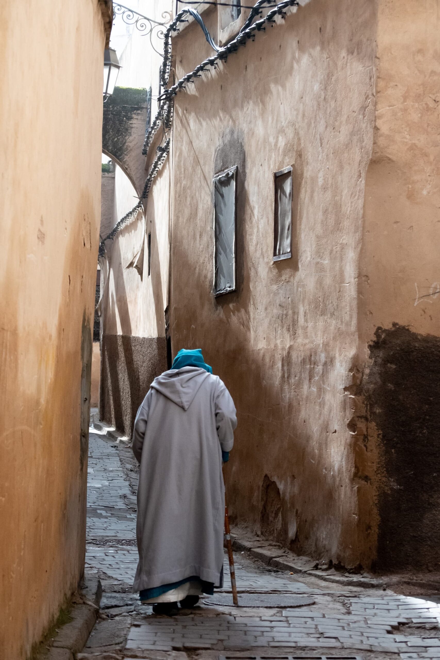 A old man walking through a narrow alleyway in Fez