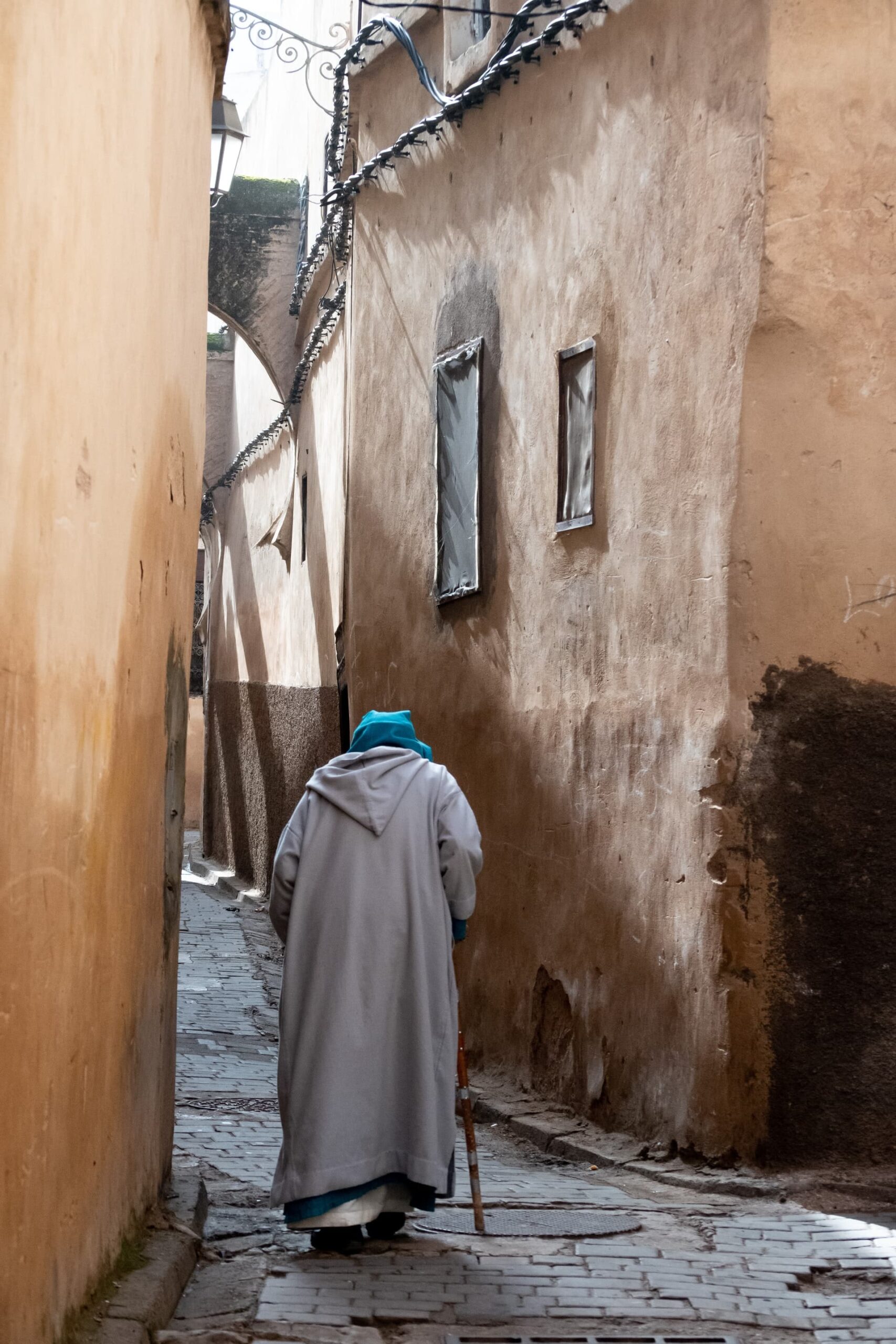 A old man walking through a narrow alleyway in Fez