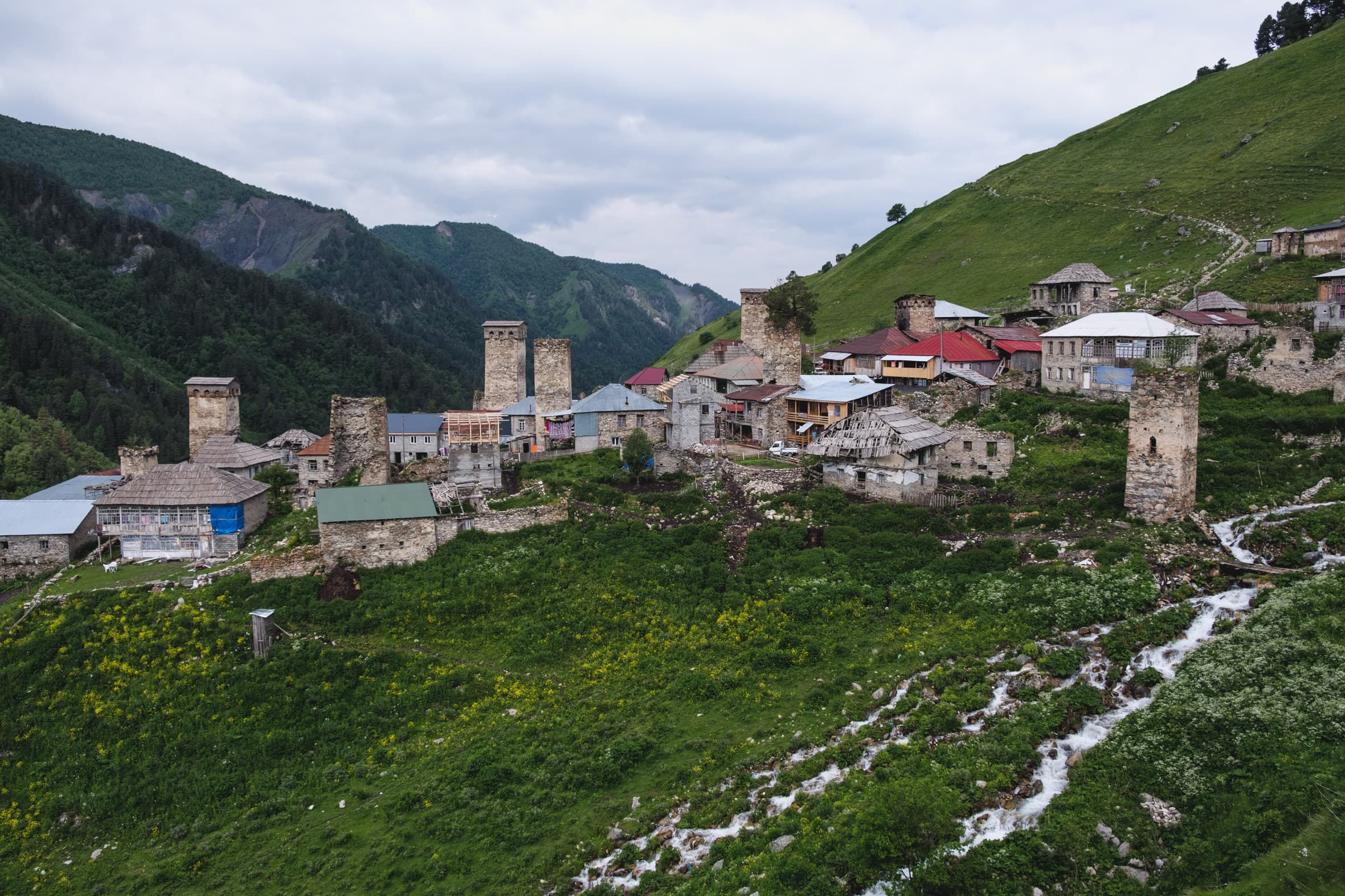 The village of Adishi with its Svan towers and a stream flowing by, situated on a mountain slope, Svaneti