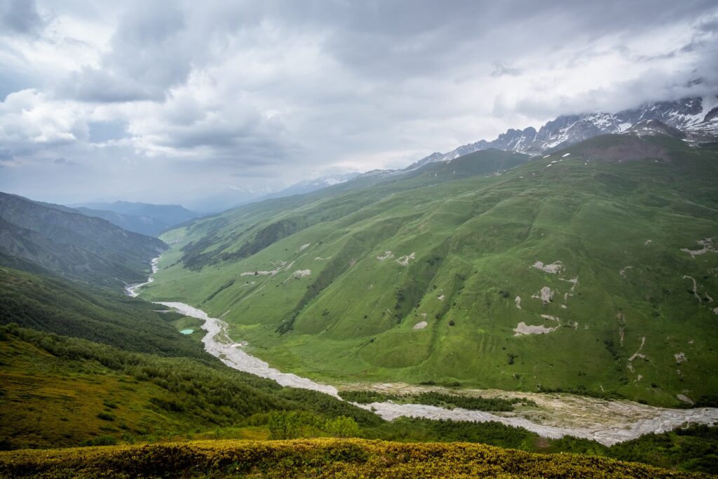 Adishischala river with lush green slopes and mountain peaks in the background, near Adishi, Svaneti
