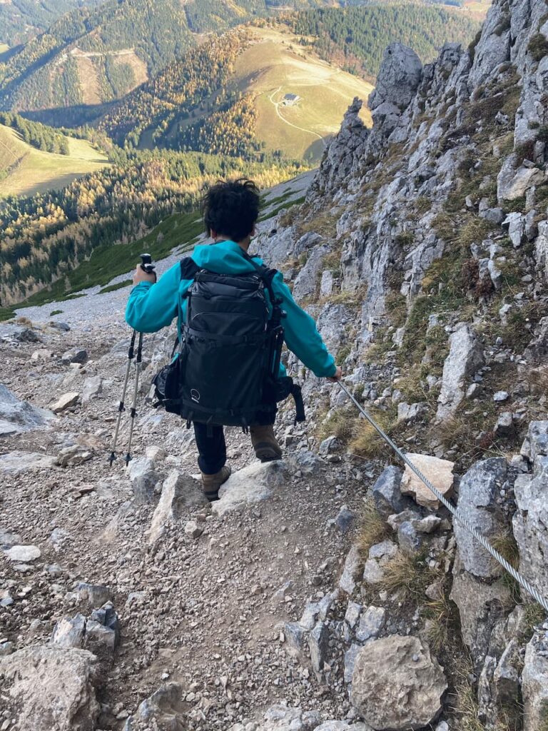 Aydin navigating the steep path down Fadensteig while holding on to a cable for balance