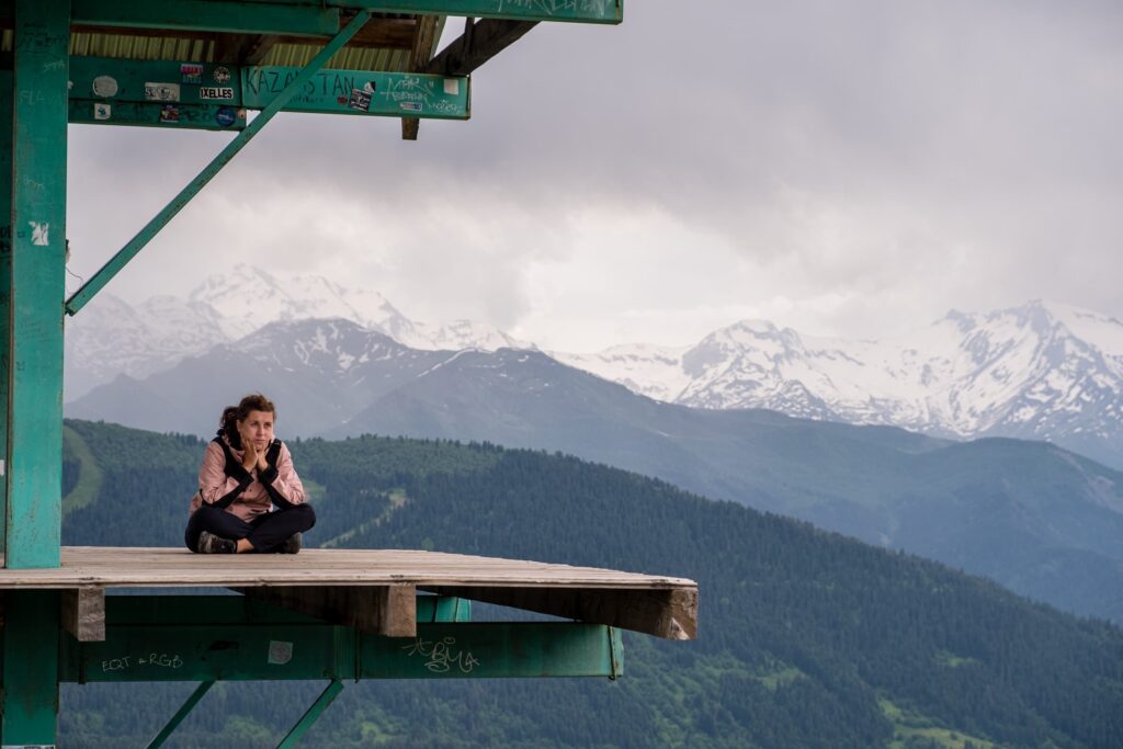 Caroline resting on the Mestia Cross lookout platform after a hard hike