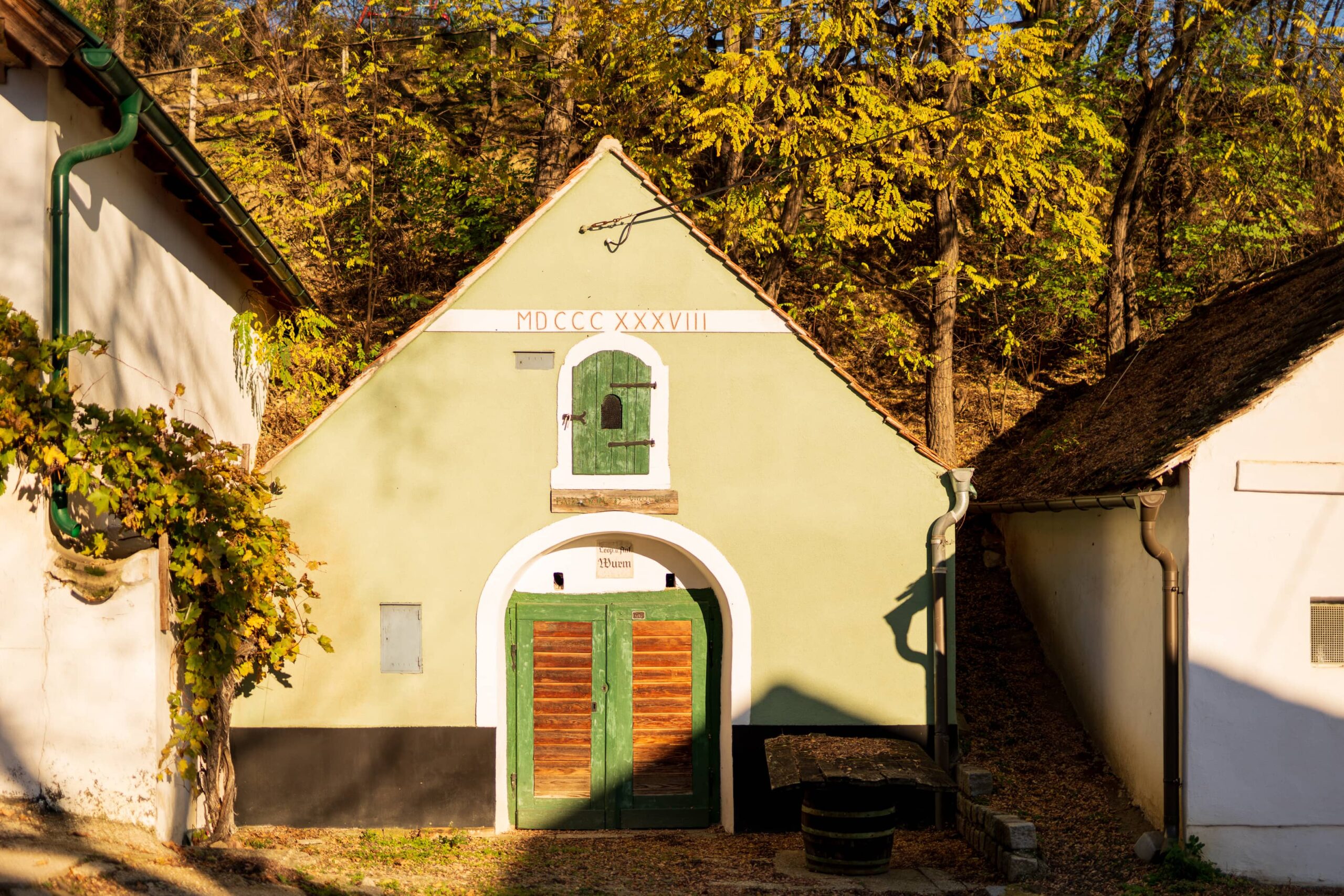 Pale-green cute triangle-shaped wine cellar building with roman numeral inscription at Große Kellertrift, Haugsdorf