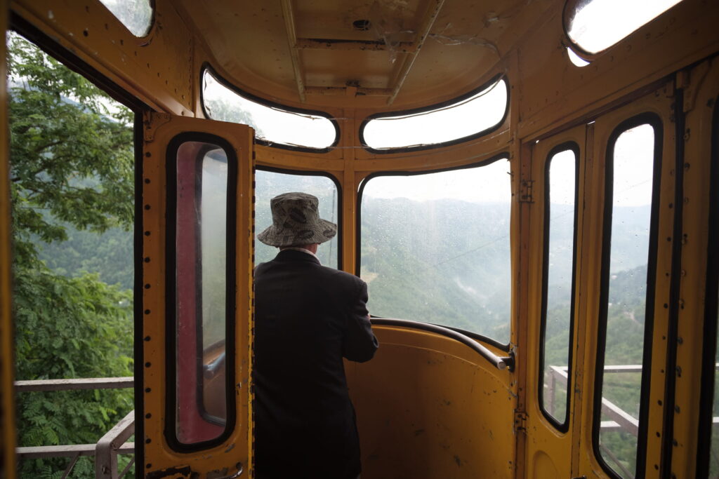 A lone man in the cable car at Khulo with green rainy landscape in the background