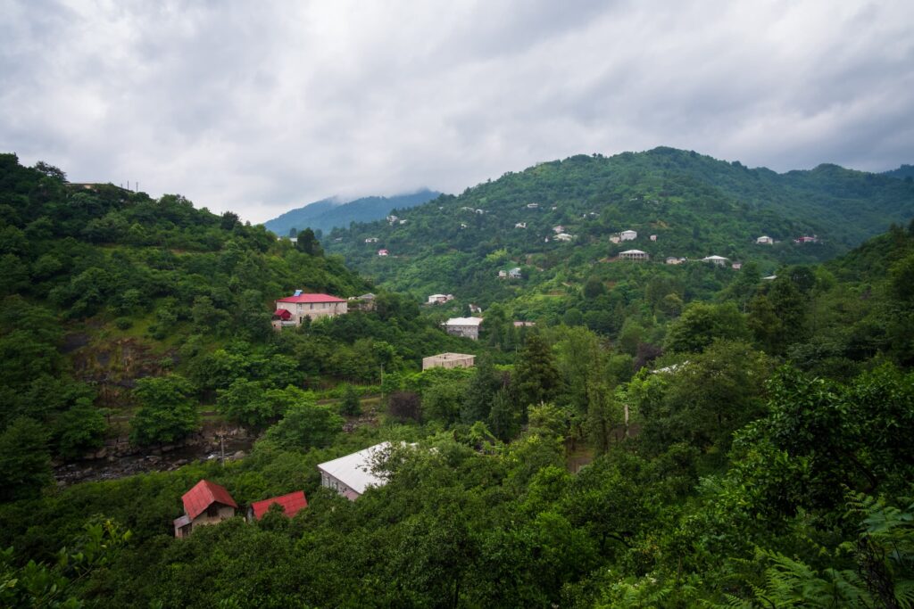 The entrance of Mtirala National Park from the road with lush green hills and forests dotted with homes
