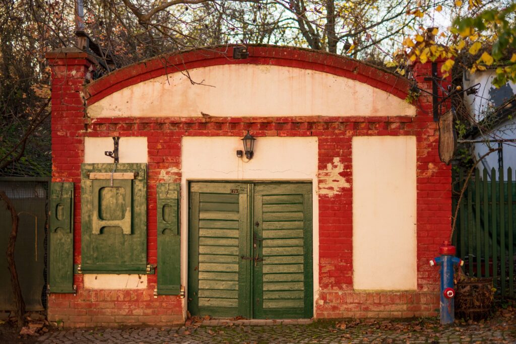 White and red-bricked wine cellar building with green door and shutters at Große Kellertrift, Haugsdorf