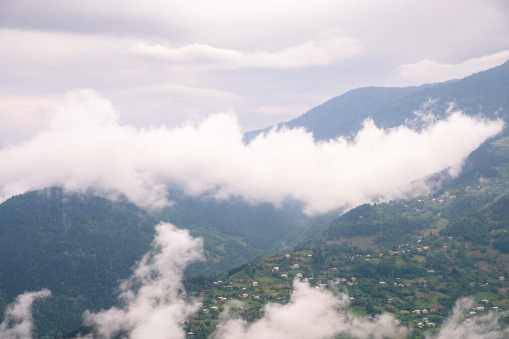 View of the houses of Tago dotted around the lush green landscape surrounded by hanging clouds