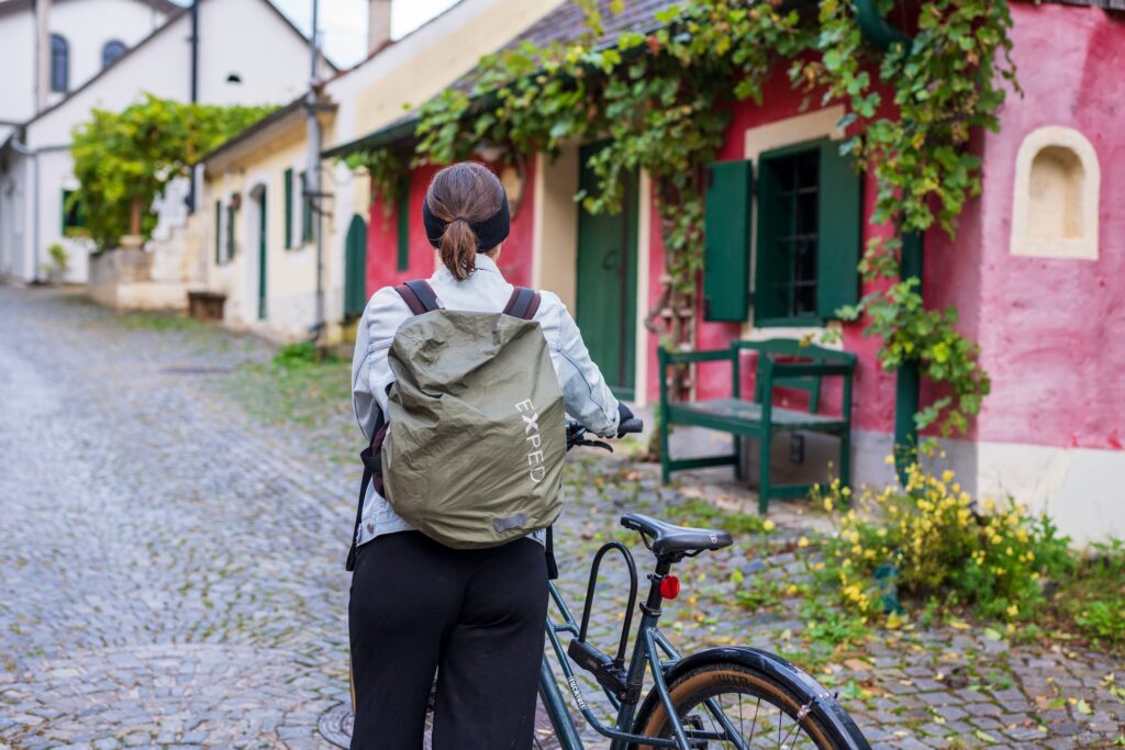 Caroline pushing her bike next to beautiful wine cellars on Rohrendorfer kellergasse