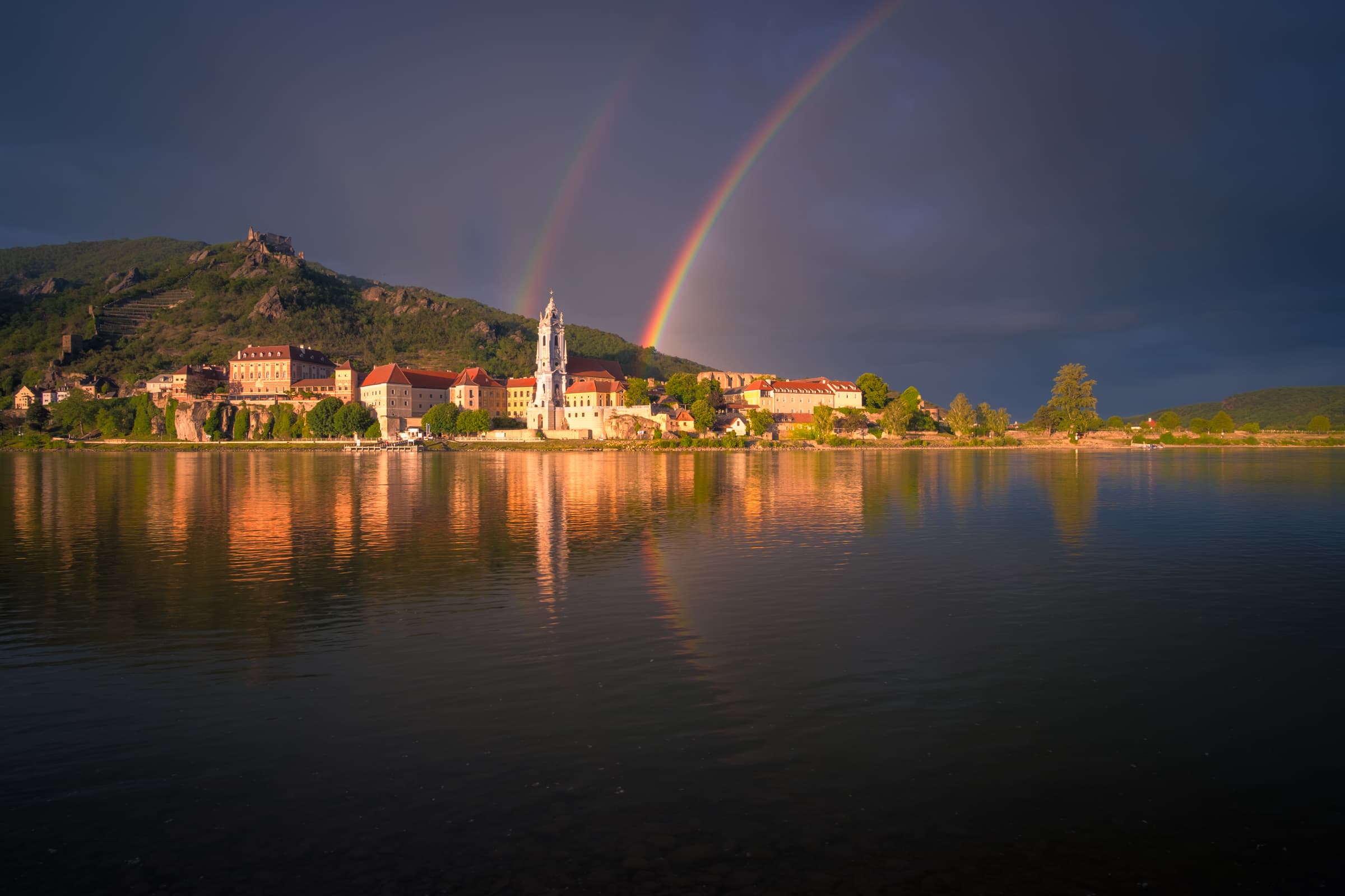Wider shot of Dürnstein, its cathedral and castle with a spectacular double rainbow across the Danube