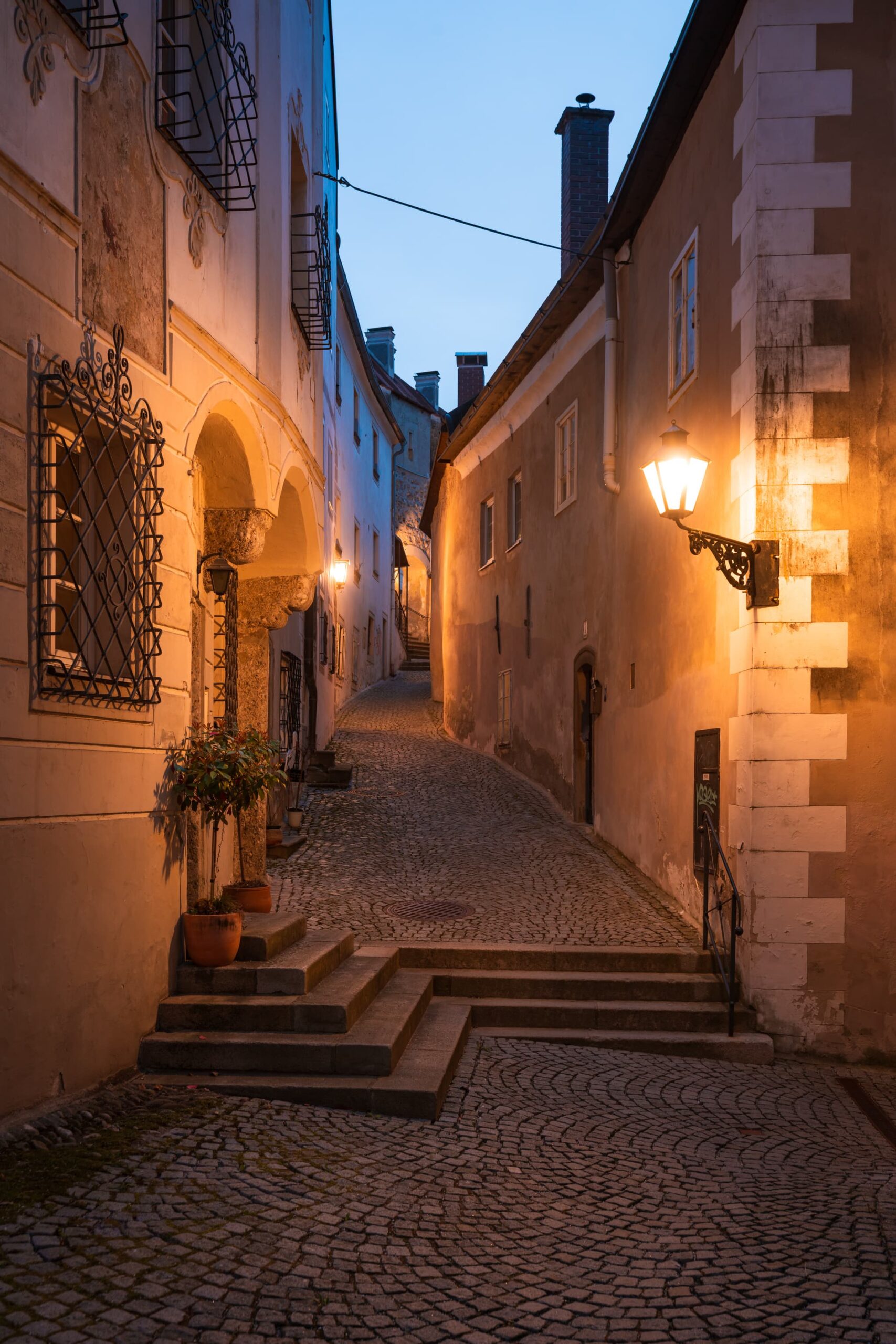 Twisting cobbled side street lit by old fashion steet lamps in Steyr
