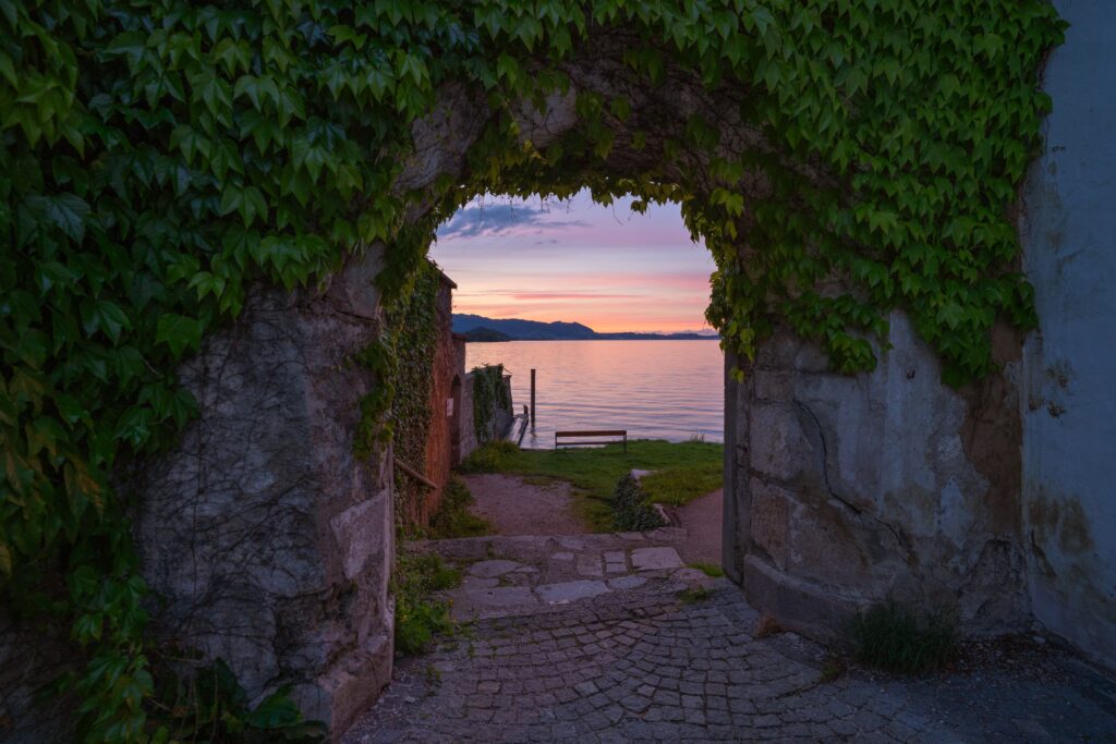 Vibrant sunset through a medieval stone arch on the Traunkirchen peninsula, looking over the lake