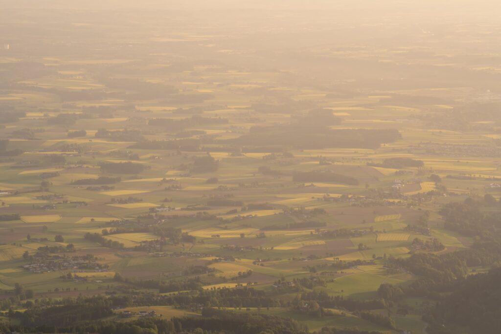 Beautiful golden light cast over the fields and small woods and forests of the lower lands from the peak of Traunstein